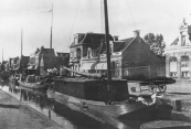 Deze tjalk ligt in Drachten aan één der kaden. Hij is geladen met turf die de schipper hier zal verkopen. Een handkar met turf staat al klaar om te worden afgeleverd. (Foto uit 1933)