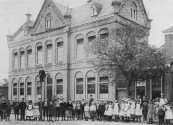 Foto van omstreeks 1900 waarbij de leerlingen van de in 1887 gebouwde Openbare Lagere school voor de fotograaf poseerden. Het pand rechts (afgebroken) werd in 1877 door 't Nut als kleuterschool gebouwd. 