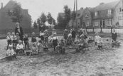 Deze grote zandspeelplaats lag voor de Nuts-kleuterschool . Naast juf. Looijenga zijn slechts enkele spelende kinderen herkend. Tinie Nauta, Piet de Jong, Geeske en Oene de Boer en Jan Visser. Op de achtergrond de eerste gemeentewoningen die kort na de eerste wereldoorlog werden gebouwd en in 2004 zijn afgebroken. 