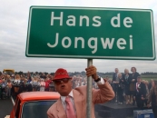 Gorredijk, sept. 2013 – Met een kinderoptocht, dansers, vuurwerk én een trimloop is donderdagavond de nieuwe rondweg om Gorredijk geopend. De weg is vernoemd naar de bekende weerman en onderwijzer Hans de Jong uit Gorredijk, die in 2010 overleed. Samen met enkele honderden Gerdyksters en hardlopers verklaarden gedeputeerde Sietske Poepjes en wethouder Wietze Kooistra de rondweg voor geopend.
Onder aanvoering van een gele cabriobus liepen de schoolkinderen uit Gorredijk naar het feestterrein. Daar voerden zij een pas ingestudeerde dans op. Met een druk op de knop onthulden weduwe Dina de Jong en burgemeester Francisca Ravestein de naam van de rondweg. Een enorme houten box klapte open en daar verscheen een autootje met de nieuwe naam erop.
