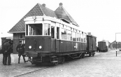 De Gooise motortram staat in Heerenveen klaar voor vertrek naar Gorredijk en Drachten. Een gelaarsde W.A. man loopt langs de personenwagen.