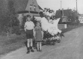 Optocht op 5 mei 1945. Hier op de Nijewei voor het huis van fotograaf H.C. v/d Meer.  Voor de versierde wagen staan Jan en Hilda Tabak. Op de wagen Billy (Sybilla) v/d Meer, een dochter van de fotograaf.