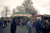 Een gezellige boel tijdens de najaarskermis van Gorredijk in het jaar 1983, met zicht in de richting van de Hoofdstraat staan o.a op de hoek van het Marktplein de attracties: Bootjesmolen van Nicholaas Rampen, Holly Cranes Nico Sipkema & zn. en de Rups van de familie Regter. (Bron: Stichting kermiscultuur)