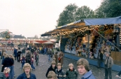 We nemen een kijkje op het Marktplein tijdens de voorjaarskermis van Gorredijk in het jaar 1978 aan deze kermis zat een speciaal tintje, er ging namelijk een gloednieuwe attractie voor de allereerste keer open voor het grote publiek. Het was weliswaar met enige vertraging maar hij kwam toch! De nieuwe Autoscooter van Nico en Doetie Buwalda-Panbakker (van oorsprong uit Leeuwarden). Rechtstreeks van de fabriek uit het Italiaanse Reggio Emilla kwam de enorme Autoscooter, een baan van 34 bij 16 meter aan waarna de opbouw kon beginnen vele handen maken ligt werkt zo dacht ook de Gorredijkster schooljeugd ze hielpen de familie Buwalda massaal mee met de opbouw van de attractie, echter kwam er een kink in de kabel.... de hele onderbouw lag namelijk net verkeerd om waarna deze weer opnieuw gelegd en gewaterpast moest worden geluk bij een ongeluk kwam op dat moment een Italiaanse monteur aan. Alles kwam op tijd klaar voor aanvang van de kermis, een kermis welke de familie een hoop gratis ritten zou kosten zei Nico Buwalda nog lachend, ach... de Gorredijksters hadden immers enorm goed geholpen en de familie kwam tenslotte ook al zo lang in Gorredijk dat hem dat niks uitmaakte. Op de achtergrond zien we de nieuwe Autoscooter van Nico en Doetie staan met op de voorgrond links de Spin van Louis Vallentgoed en rechts de grote Bingo tent van Dicky van Griensven i.s.m. Nico Sipkema. Laatst genoemde staat ook bij vele Gordyksters in het geheugen gegrift vele jaren stond de familie Sipkema met hun zonen Corry (Cornelis) & Henny (Hendrik) in Gorredijk met o.a. hun oh zo bekende Autoscooter en Holly Cranes. (Foto: Stichting kermiscultuur)