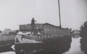 De met turf hoog opgetaste schuit van schipper Beyert van Drachten nadert van het zuidoosten uit de Boppedraai. De turf is afkomstig uit Drenthe. De foto werd in 1945 gemaakt.