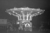De fraaie opgooi Zweefmolen van de vooral in Friesland bekende Rapke Tuinstra uit Drachten. Rapke stond diverse keren op de kermis van Gorredijk, tijdens welke editie deze foto genomen is is niet precies duidenlijk maar het zal zo omstreeks 1958 geweest zijn. Rechts van de attractie is de in/uitgang van de Nieuwstraat te zien. (foto: SKC)