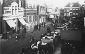 De Noord- Oost Dubbelestraat (Nu Hoofdstraat) tijdens de najaarsmarkt in oktober 1935, met Schansburg op de achtergrond. Rechts vooraan het reclamebord van bakker Gerrit Bruinsma die hier in 1934 was gekomen na het fallissement van bakker Sikke Hoekstra. In datzelfde jaar 1934 had Jelle Durks Sijtema het huis met winkel links van Obe Geerts Tasma gekocht.