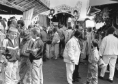 Deze afgebeelde foto is gemaakt tijdens de najaarskermis op zondag 25-10-1987, de mensen zijn in grote getale aanwezig op het marktterrein en vermaken zich uitbundig aan o.a. de op de foto zichtbare Autoscooter van de familie Buwalda en de Cake Walk met orgel van de familie Klinkhamer.
