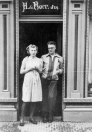 Romkje en Jelle in de deur van de bakkerswinkel in de Hoofdstraat, waar zijn ouders woonden